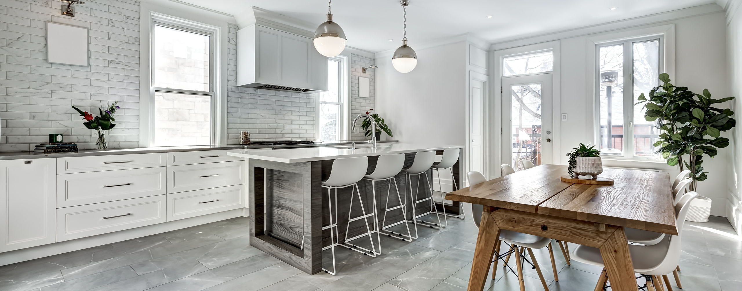 Modern kitchen renovation featuring white cabinetry, tiled backsplash and marble countertops
